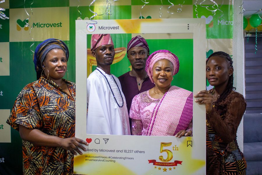 Colleagues in traditional attire holding the 5th anniversary frame