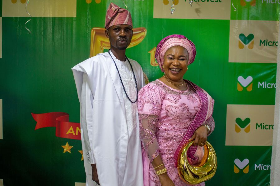 Two guests dressed for the celebration in front of the Microvest backdrop